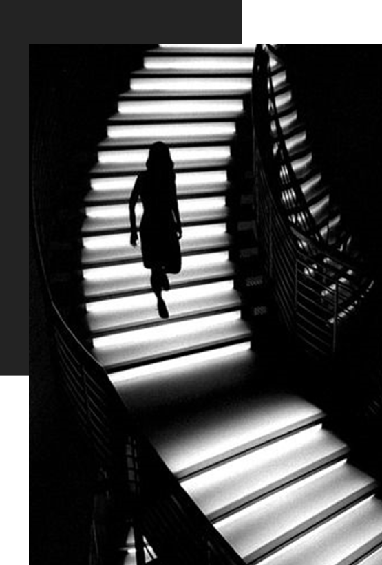 Silhouette of a person walking down illuminated stairs.